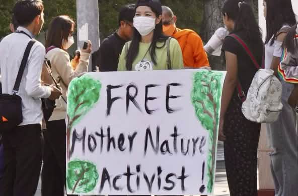 Mother Nature Activist! Seorang aktivis mengangkat plakat menghadap kamera dengan tulisan „Free Mother Nature Activist!