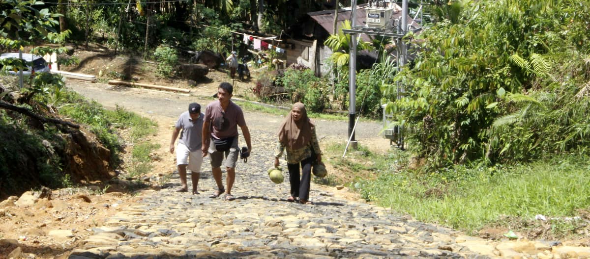 Tiga warga di jalan berbatu di sebuah desa di hutan