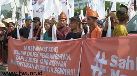 Massa denga topi adat dan spanduk "Masyarakat adat bukan obyek pembangunan!"