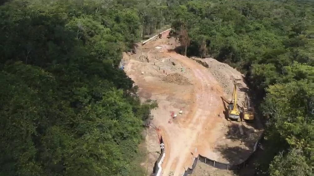 Foto pembangunan saluran pipa bauksit di hutan hujan dengan eskavator yang mengaduk-aduk tanah dan meletakkan pipa