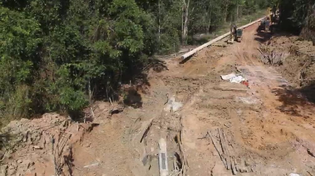 Foto pembangunan saluran pipa bauksit di hutan hujan dengan eskavator yang mengaduk-aduk tanah dan meletakkan pipa