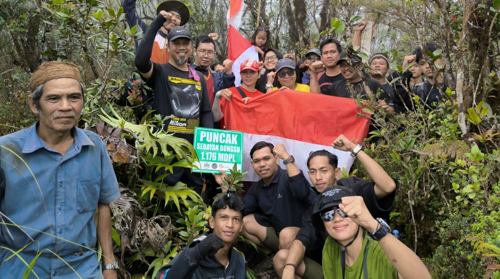 Tim pendaki yang ceria dengan bendera di dalam hutan