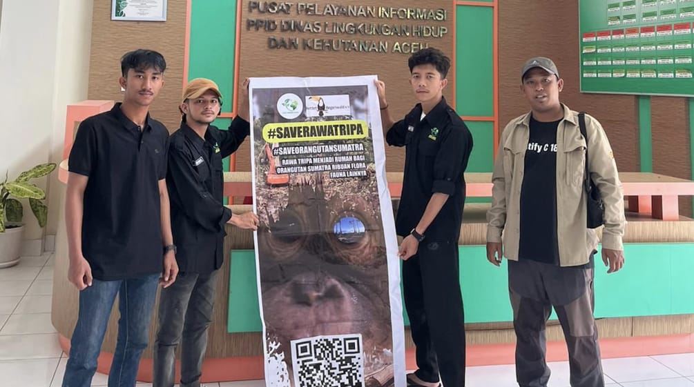 empat orang dengan spanduk besar #SaveRawaTripa di gedung Dinas Kehutanan Aceh