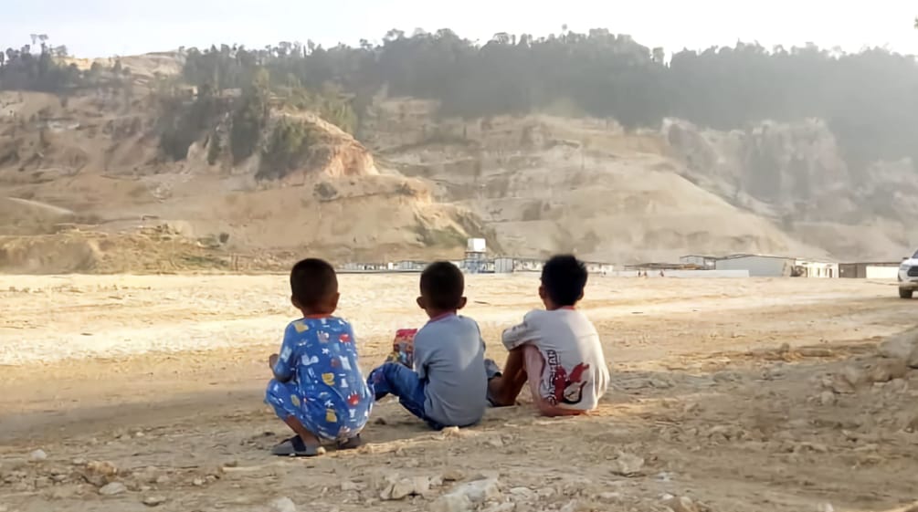 Tiga anak kecil memandang pertambangan pasir